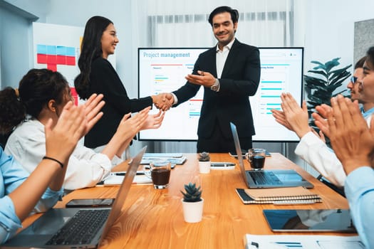 Cheerful meeting room, businesspeople celebrate with handshaking. Successful project was completed before the deadline. Business partnership and collaboration in project management. Habiliment