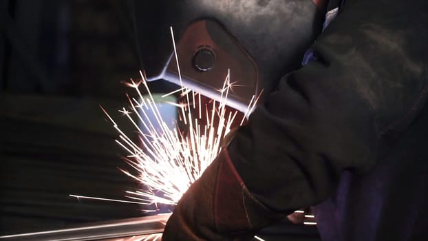 A man works with a welding machine. Clip. Welding steel structures in the factory. Beautiful sparks fly out.