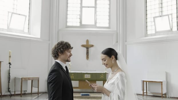 The wedding vow in the church. Action.The newlyweds standing in a large temple decorated with crosses and give each other an oath. High quality 4k footage