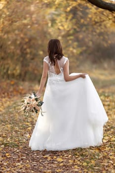 beautiful happy bride holding wedding autumn bouquet in nature