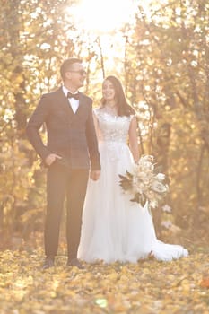 beautiful wedding couple standing together holding hands on natural background in sunny day