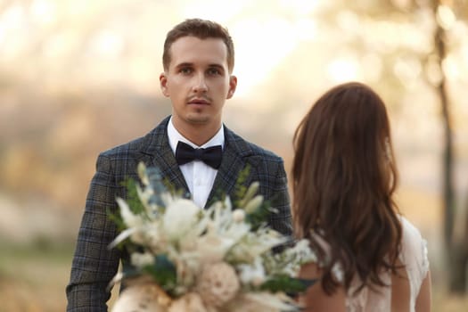 portrait of bride in white wedding dress and groom standing outdoor on natural background