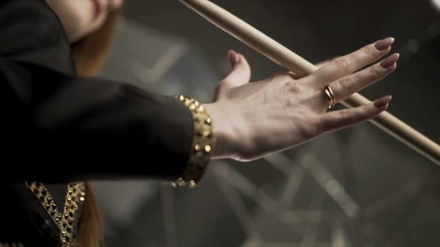 Young attractive woman hand holding drumstick and rotating it during musical rehearsal. Close up for woman hand with manicure and gold rings holding and spinning a drumstick.