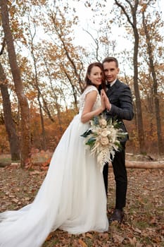 beautiful sensual bride in white wedding dress and groom standing outdoor on natural background