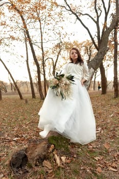 beautiful happy bride holding wedding autumn bouquet in nature