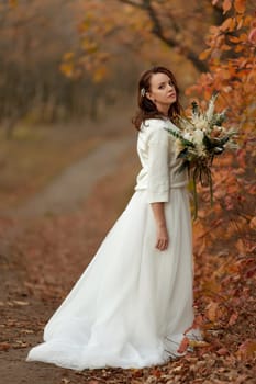 beautiful happy bride holding wedding autumn bouquet in nature