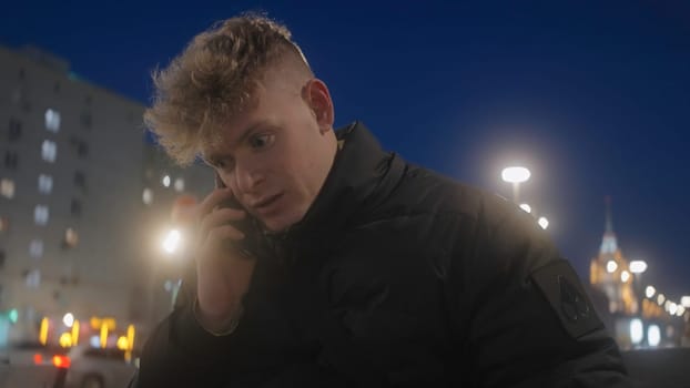 Young man is talking on phone on background of modern city. Action. Man is talking on phone while walking around city.