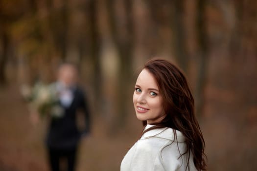 portrait of beautiful happy bride and blur groom holding wedding autumn bouquet on the background