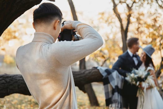 Professional wedding photographer taking pictures of the bride and groom in nature in autumn