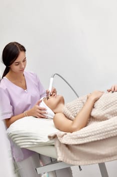cosmetologist making procedure microdermabrasion on the face in beauty salon