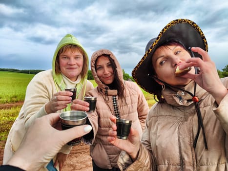 Middle-aged women or girls in the field in nature with glasses celebrating something on a hike. Funny and happy Women in camping and travel