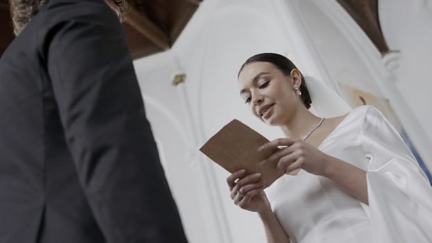 The wedding ceremony in the church. Action.Beautiful newlyweds with a bright spectacular bride in a white dress and a groom in a suit who take vows at their wedding. High quality 4k footage