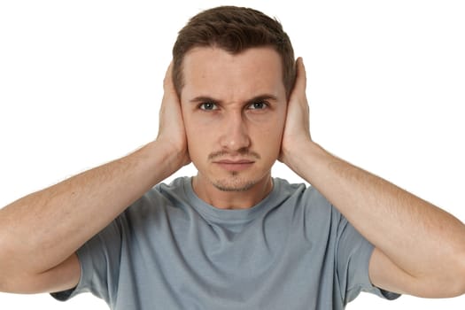 caucasian man in t-shirt covers ears with hands on white background