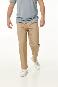 man wearing white sneakers and casual beige pants and walking on studio background