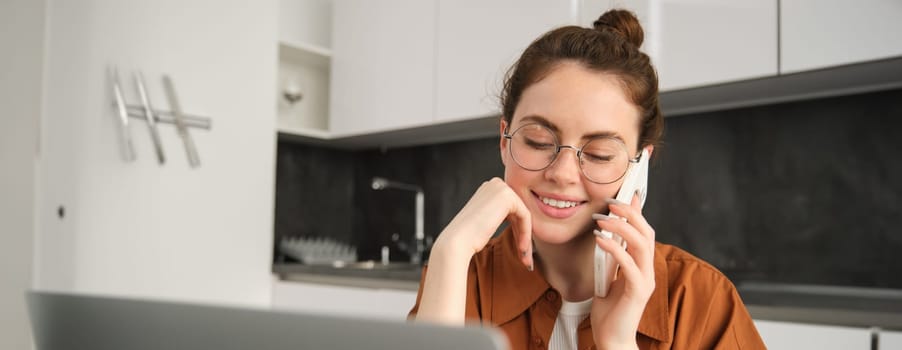 Portrait of young woman at home, doing online shopping. Businesswoman has own start-up making a phone call, has conversation with client, saleswoman trading online, using laptop.