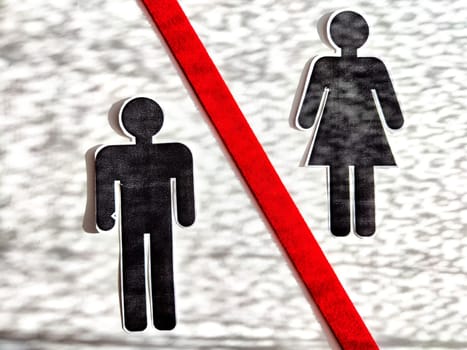 The concept of divorce, quarrels, and separation of a couple. Paper black figurines of a man and a woman separated by red line. Abstract background, texture