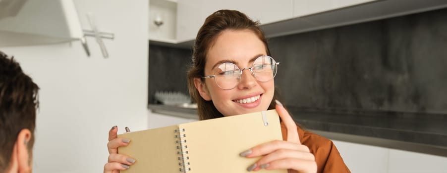 Portrait of cute smiling woman reading her notes, holding notebook.