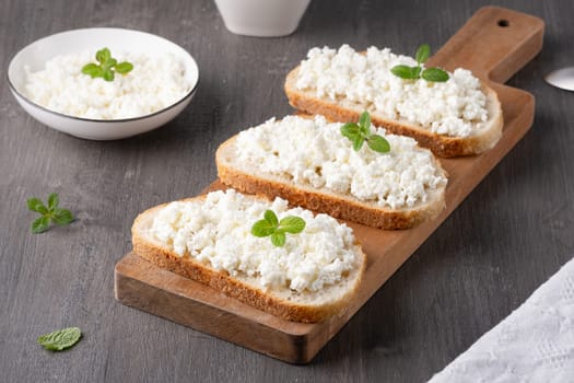 Bread with curd cheese on wooden board.