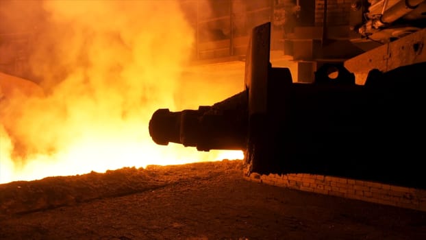 Molten steel pouring process with steam clubs at metallurgical plant. Close up fot steel pouring machine.