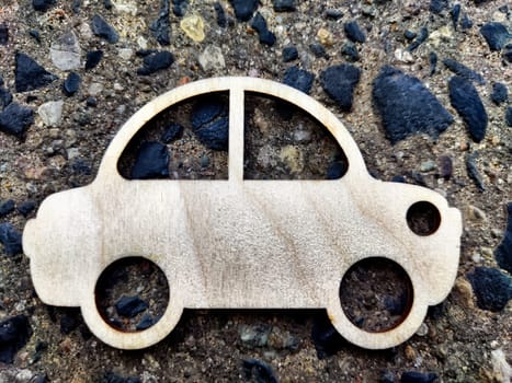 The small wooden toy car on stone texture, grey background. The concept of travel, car buying, transportation use. Space for text, frame, copy space