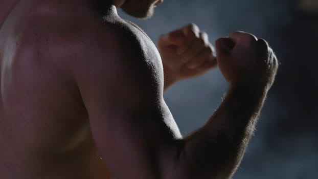 Punches close up in smoke dark background. Muscular kickbox or muay thai fighter punching in smoke