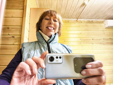 Middle-aged woman using smartphone for selfie and blogging. Female blogger poses in a photo. The girl admires herself in the mirror