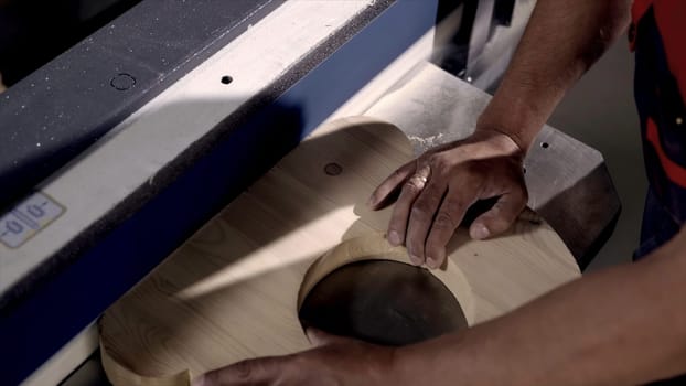 Close-up of man grinds wood products on industrial machine. Action. Carpenter polishes wooden product for tape manufacturing machine.