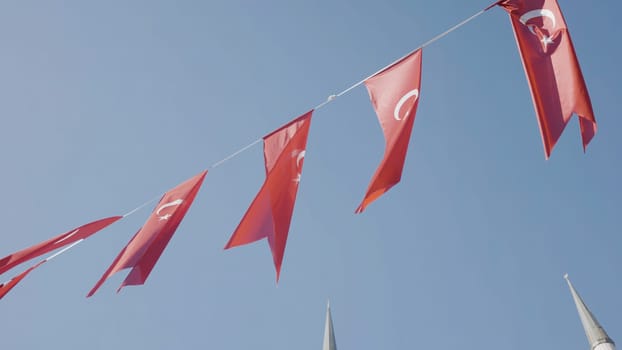 Turkish flags on rope. Action. Flags of Turkey are festively hung on rope on background of blue sky. Flags of Turkey hang beautifully and wave in wind. Turkish Holiday and Patriotism.