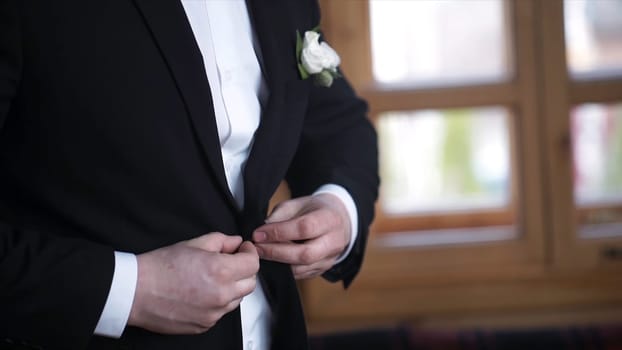 Man buttoning on a black jacket. Wedding details - elegant groom dressed wedding tuxedo costume is waiting for the bride. businessman buttoning jacket, getting dressed. Groom buttons jacket HD