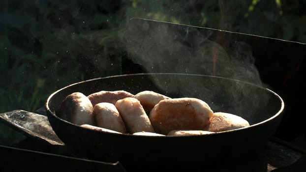 Frying hot mini pies outdoors during picnic. Creative. Gastronomy and takeaway food concept, heating pies in a pan