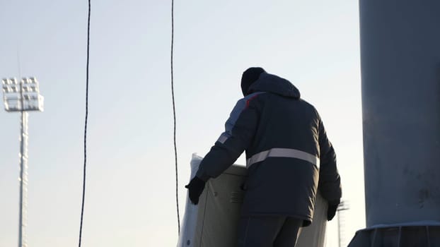 Man assemble Billboard. A man collects parts of the Billboard for advertising in the winter time.