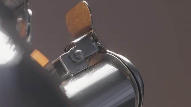 Close up of spinning closed short spout of a metal silver kettle on blurred grey wall background. Action. Spinning new teapot