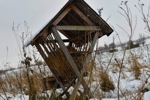 A snowy hay rack in the winter. A feeder rack filled with hay and ready for winter feeding of game. Concept of the end of the game season and preparation for winter feeding of wild game.