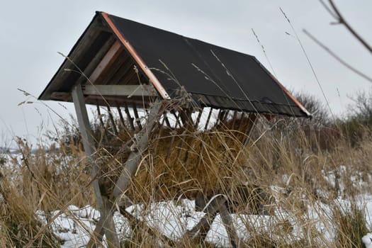 A snowy hay rack in the winter. A feeder rack filled with hay and ready for winter feeding of game. Concept of the end of the game season and preparation for winter feeding of wild game.