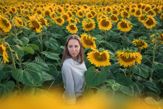 Portrait of beautiful woman posing in field with sunflowers, enjoying nature and summer.