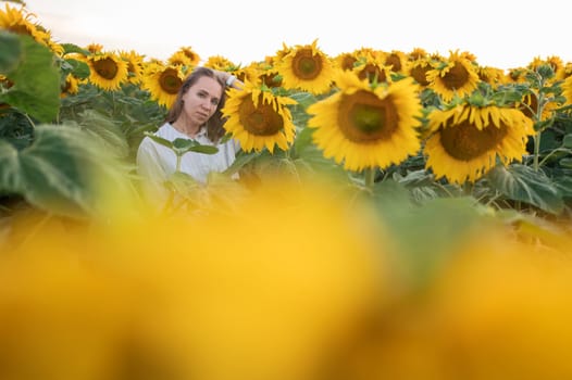 Portrait of beautiful woman posing in field with sunflowers, enjoying nature and summer.