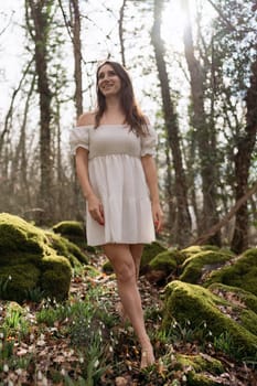 Snowdrops galanthus woman. She stands in a white dress on a meadow with snowdrops in a spring forest.