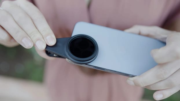 Close up of woman putting removable lens for smartphone on its camera. Action. Concept of technologies