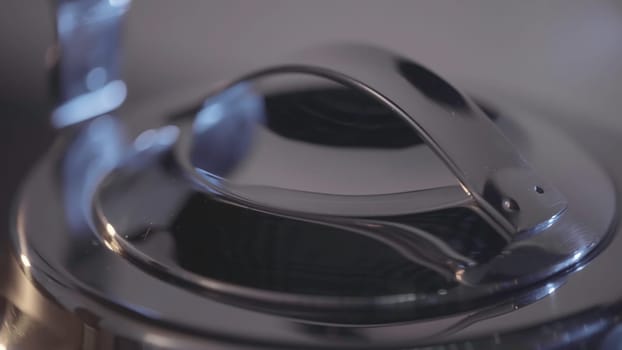 Lid of metal teapot. Action. Close-up of beautiful metal parts of kettle. Stylish Steel Kettle for boiling Water. Shiny details of new metal teapot.