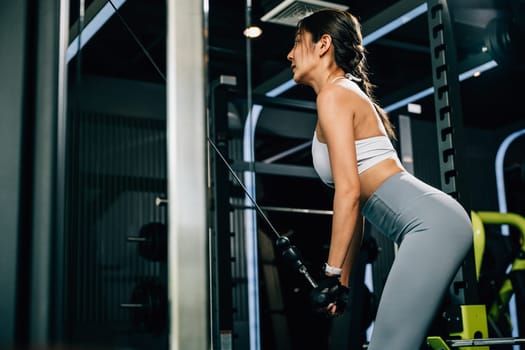 Young woman in sportswear exercising on a pulldown weight machine, working on her upper body strength and resistance training. fitness center health workout concept