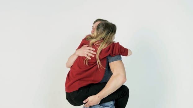 Guy turns the girl on hands. Young man turns the girl on hands on white background.