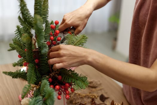 Woman making Christmas arrangement with fir branches. craft handmade decor.