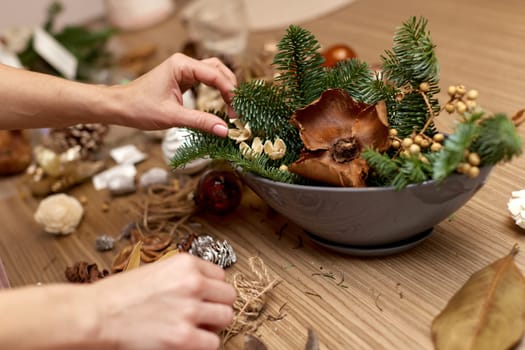 Woman making Christmas arrangement with fir branches. craft handmade decor.