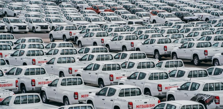 Lamchabang, Thailand - July 02, 2023 Rows of new cars parked in a distribution center at a car factory on a cloudy daya top view reveals the crowded parking, symbolizing modern industry and business.