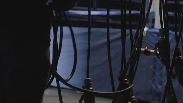 Silhouette of a man repairing concert equipment. The stage worker sets up the lights