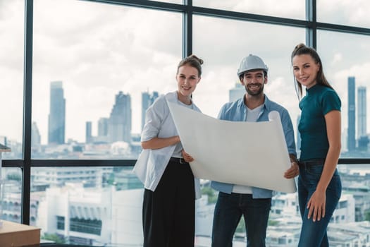 Group of smart architect engineer looking at camera while holding project plan. Skilled manager team discuss about building construction while standing near with city view. Team working. Tracery.