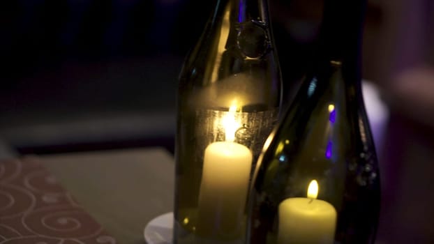 Decorative bottles with candles inside. Candles inside small bottle. Summer homemade decoration, glass jar and bottle, led candle flame light inside.