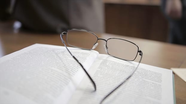 White notebook with glasses on wooden table. Glasses teacher on the table.