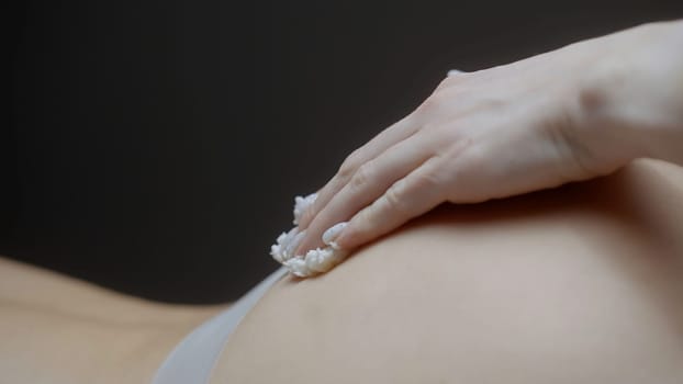 Female masseur hands applies natural scrub and massages buttocks. Action. Exfoliation mask beauty treatment. Luxury treatment at SPA salon