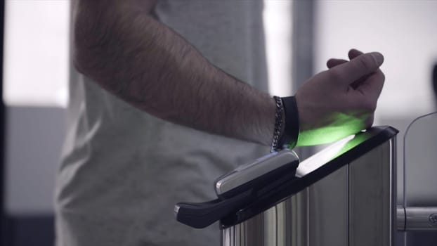 Close-up view to turnstile. Frame. Electronic access control security system indoor side view. Close-up view of hand of man applying pass to turnstile.